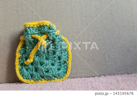 Crocheted bag in green and yellow yarn on a gray background Crocheted bag in green and yellow yarn on a gray background 143195676