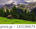 Alpine mountain cabin beneath dramatic peaks 143196679