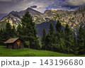 Alpine cabin beneath a dramatic mountain range 143196680