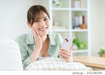 リビングでスマホを使う若い女性 143196764