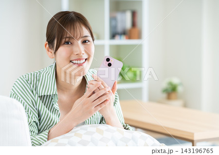 リビングでスマホを使う若い女性 143196765