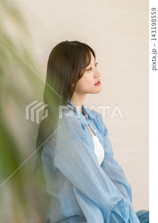 自然光の中でくつろぐロングヘアの20代女性。ナチュラルな横顔とカジュアルファッション 自然光の中でくつろぐロングヘアの20代女性。ナチュラルな横顔とカジュアルファッション 143198559