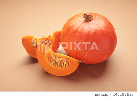Half of Hokkaido pumpkin on brown background. Space for text Half of Hokkaido pumpkin on brown background. Space for text 143198616
