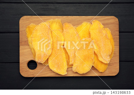 Slices of dried mango on cutting board on black background. Space for text 143198633