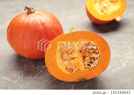 Sliced Hokkaido pumpkin with seeds on grey concrete background. Sliced Hokkaido pumpkin with seeds on grey concrete background. 143198641
