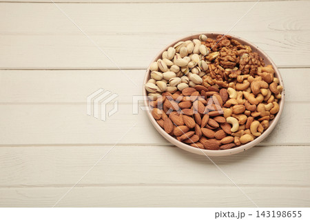 Mix of various nuts on plate on light background. Pistachios, cashews, walnuts, hazelnuts, peanuts. Space for text Mix of various nuts on plate on light background. Pistachios, cashews, walnuts, hazelnuts, peanuts. Space for text 143198655