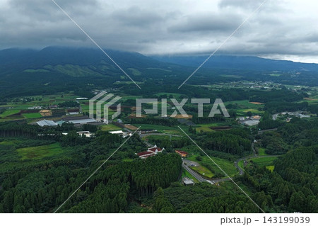 宮崎県小林市の針葉樹林・田畑・大型倉庫建屋を捉えた空撮写真 143199039
