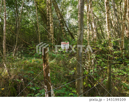 Warning Sign on Metal Wire Mesh Fence in Green Forest 143199109
