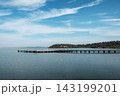 Calm lake and wooden pier under a blue sky with fluffy clouds. 143199201