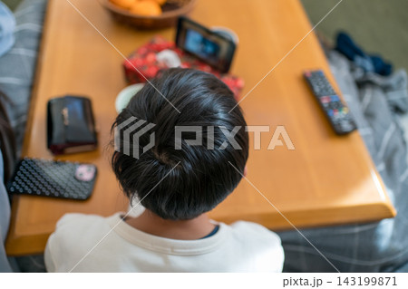 こたつに座る13歳の男の子の後ろ姿 こたつに座る13歳の男の子の後ろ姿 143199871