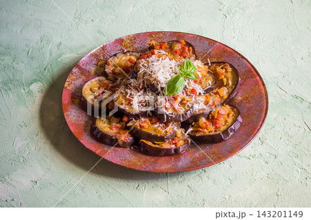 Italian Melanzane alla Parmigiana or baked eggplant slices with tomato sauce and grated cheese, top view angle. Italian Melanzane alla Parmigiana or baked eggplant slices with tomato sauce and grated cheese, top view angle. 143201149
