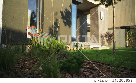 Contemporary home exterior showcasing architectural design with a well-maintained garden, green lawn, and decorative shrubs Contemporary home exterior showcasing architectural design with a well-maintained garden, green lawn, and decorative shrubs 143201952