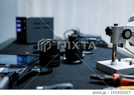 Close-up of camera lenses, tools and electronic equipment on a workbench in a photography repair workshop. 143202027