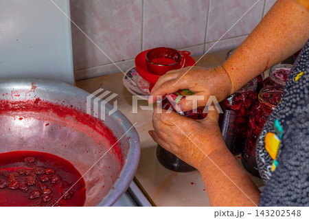 Hands Preserving Strawberry in Glass Jars 143202548