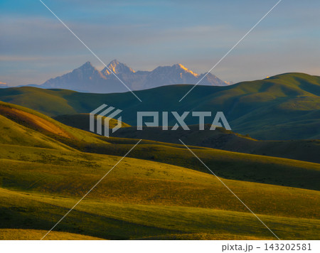 Golden Hour Over Rolling Hills and Snow-Capped Mountains Golden Hour Over Rolling Hills and Snow-Capped Mountains 143202581