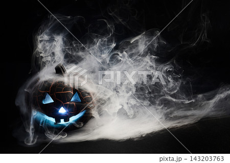Glowing jack-o-lantern surrounded by eerie blue smoke on halloween night Glowing jack-o-lantern surrounded by eerie blue smoke on halloween night 143203763