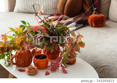Autumn cozy still life with pumpkins and leaves on white table inside warm home setting 143203813