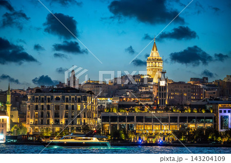 Istanbul,turkey,august 4, 2025. Illuminated galata tower standing above the bosphorus waterfront, showcasing istanbul's vibrant architecture and a yacht cruising at twilight Istanbul,turkey,august 4, 2025. Illuminated galata tower standing above the bosphorus waterfront, showcasing istanbul's vibrant architecture and a yacht cruising at twilight 143204109