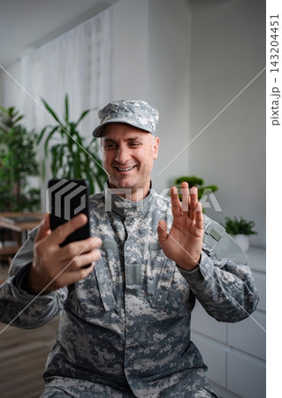 Smiling soldier making a video call with his family Smiling soldier making a video call with his family 143204451