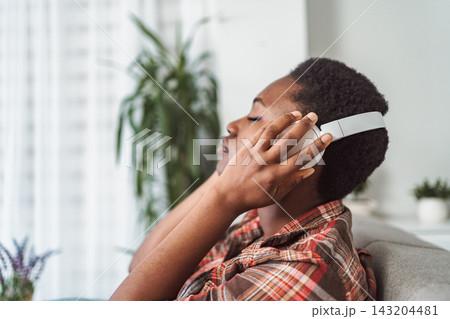 Young woman relaxing on sofa enjoying music with headphones Young woman relaxing on sofa enjoying music with headphones 143204481