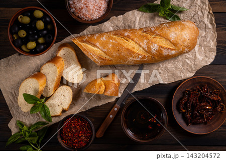 Baguette slices with olives, sundried tomatoes, and spices Baguette slices with olives, sundried tomatoes, and spices 143204572