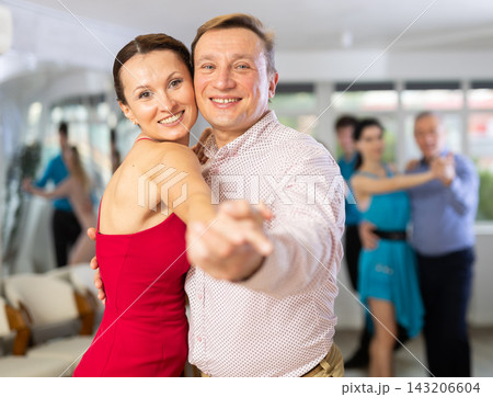 Happy people of different ages dancing tango in pairs in dance hall Happy people of different ages dancing tango in pairs in dance hall 143206604