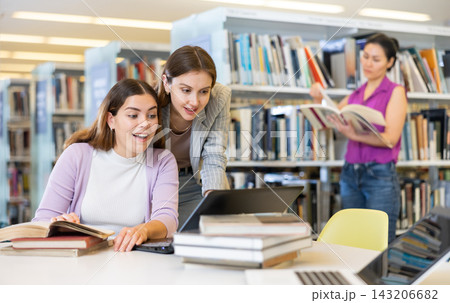 Two female students are preparing for the exam in the library Two female students are preparing for the exam in the library 143206682