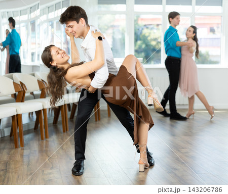 Couple in evening dresses enjoys pair dance tango, interacting with each other on floor 143206786