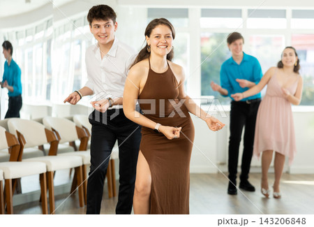 Couple in evening dresses enjoys pair dance boogie-woogie, interacting with each other on floor Couple in evening dresses enjoys pair dance boogie-woogie, interacting with each other on floor 143206848
