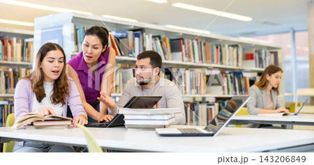 Group of friendly students working on joint research in library 143206849