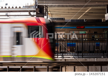駅のホームを通過する赤とシルバーの電車の流し撮り、列車の行き交う通勤や通学の日常風景 143207151