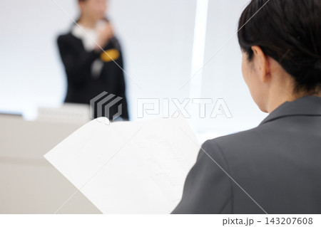 ビジネスセミナーで手元の資料を確認しながら受講する女性 ビジネスセミナーで手元の資料を確認しながら受講する女性 143207608
