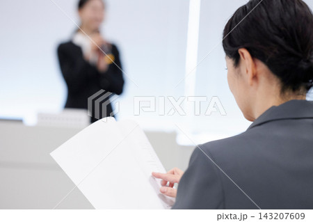 セミナーで資料を確認しながら真剣に受講する女性 143207609