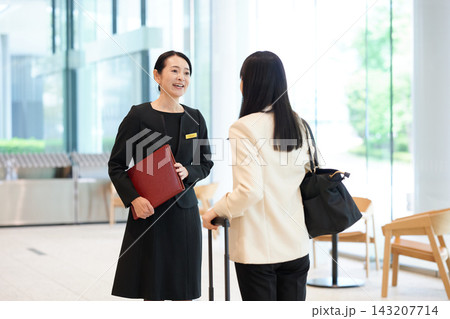 ホテルのロビーで利用客に笑顔で案内をするスタッフの女性 143207714