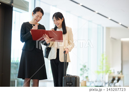 出張先で笑顔で資料を確認するビジネスウーマンの二人 出張先で笑顔で資料を確認するビジネスウーマンの二人 143207723