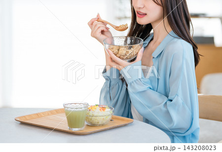 健康的な朝食を食べる若い女性(サラダ,シリアル,スムージー) 健康的な朝食を食べる若い女性(サラダ,シリアル,スムージー) 143208023