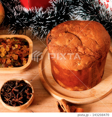 Classic panettone in a Christmas setting on a decorated rustic wooden table. 143208470
