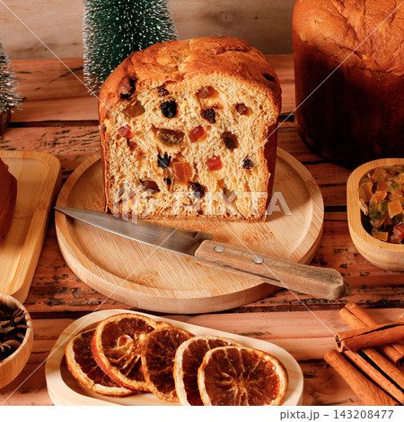 Festive Christmas panettone with candied fruit and raisins, sliced a decorated table. Festive Christmas panettone with candied fruit and raisins, sliced a decorated table. 143208477