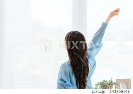 朝の窓辺で気持ちよくストレッチする若い女性の後ろ姿 143209148