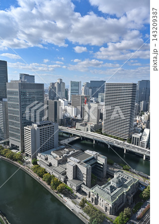 青空の下に広がる大阪・淀屋橋の高層ビル群と川沿いの都市景観を縦構図で捉えた風景写真【大阪風景写真】 143209387