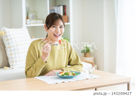 家でサラダを食べる若い女性 143209427