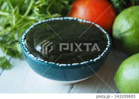 Salsa verde made from fresh ingredients sits on a wooden table 143209685