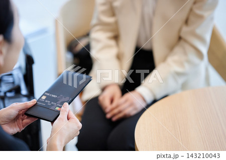 受付や店舗でクレジットカード決済を行う手元と接客シーン 143210043