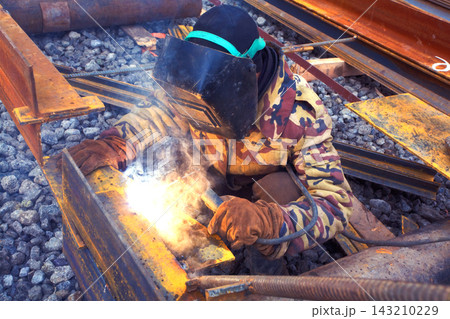 Welder in mask welding metal construction on open air. Welder in mask welding metal construction on open air. 143210229