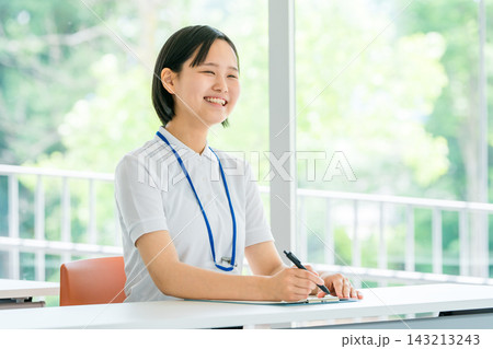 介護施設で笑顔で対応する若い女性介護職員。研修や人材育成をイメージしたスタッフ写真 143213243