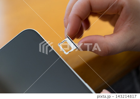 スマートフォンから空のSIMカードトレイを引き出す手元 スマートフォンから空のSIMカードトレイを引き出す手元 143214817