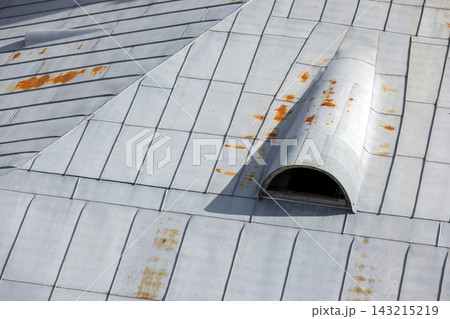 Rusted metal roof panels with a curved dormer vent reveal weathered industrial texture 143215219