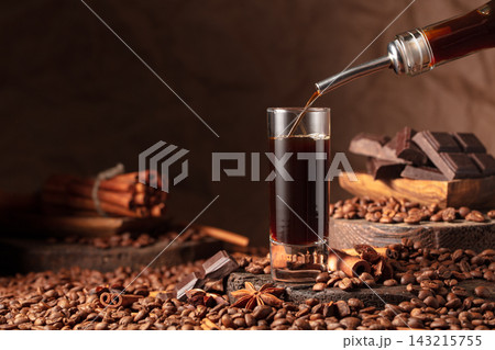 Coffee liquor is poured from a bottle into a glass. 143215755