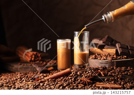 Irish cream and coffee liquor is poured from a bottle into a glass. Irish cream and coffee liquor is poured from a bottle into a glass. 143215757