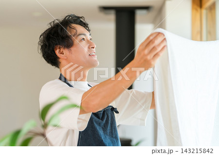 洗濯した白いタオルを広げて仕上がりを確認する男性。ふんわり柔らかな洗濯物と快適な暮らし 143215842